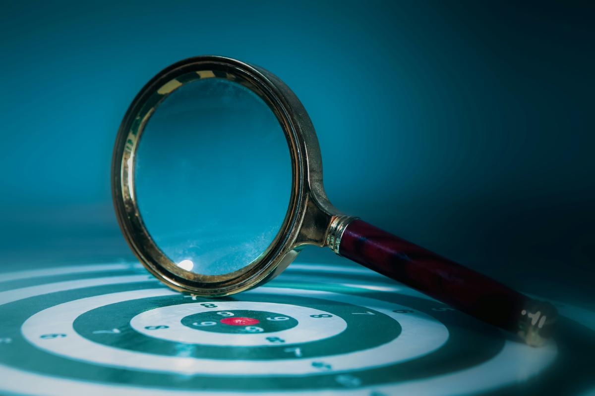 A red-handled magnifying glass over a teal dial face.